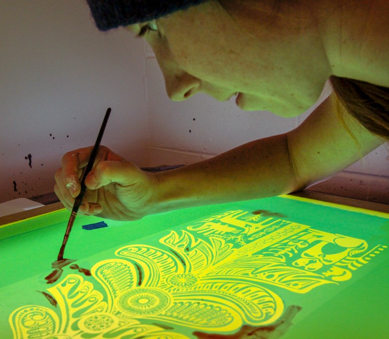 Klara Maisch fills in holes on screen before screen printing.