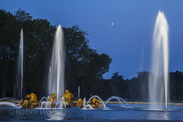 A crescent moon begins to rise over the fountain.