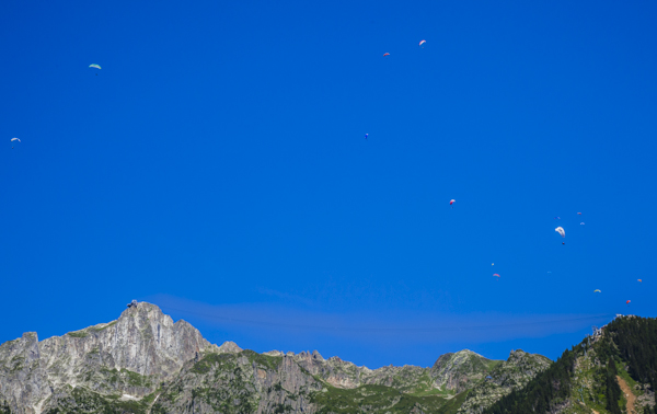 Paragliders pepper the sky, cable-car wires hardly be seen stretching from one mountain peak to the other. 